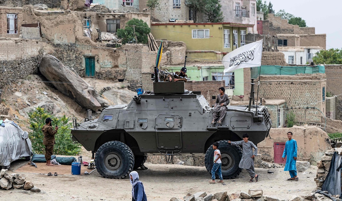 أفراد أمن من «طالبان» يجلسون فوق دبابة مدرعة تحمل علم الحركة (أ ف ب)