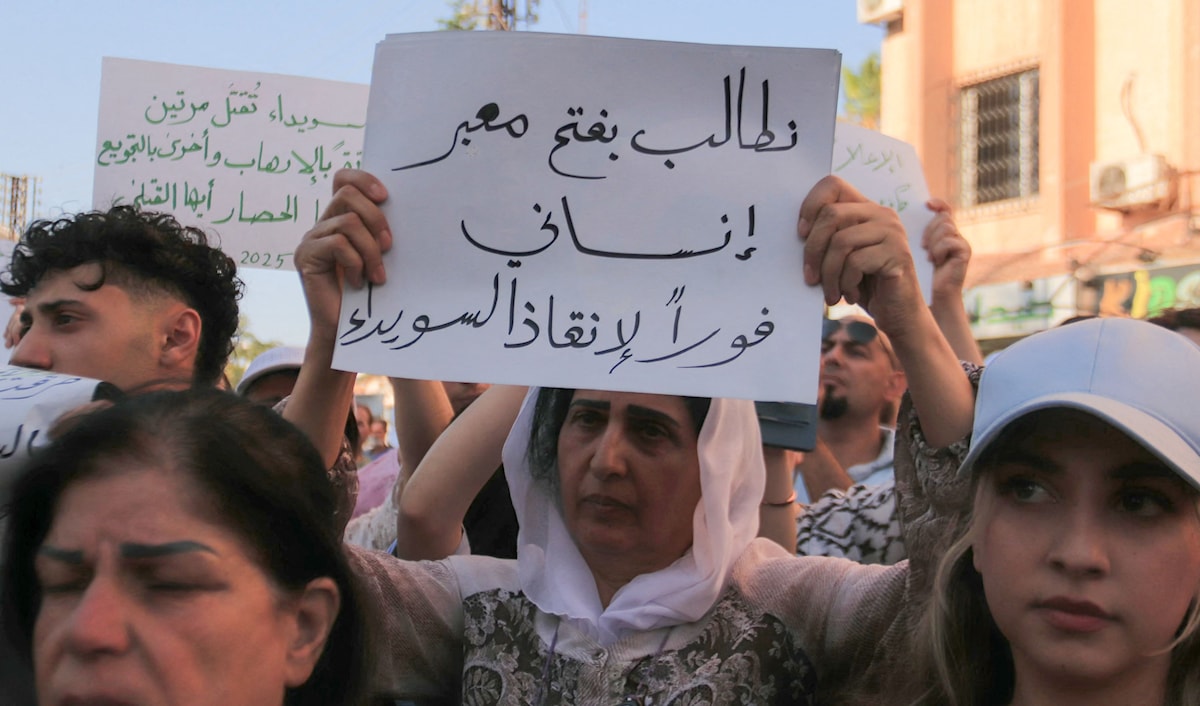 رفع المتظاهرون لافتات طالبت بفتح ممر إنساني نحو الأردن أو مناطق سيطرة «الإدارة الذاتية» (أ ف ب)