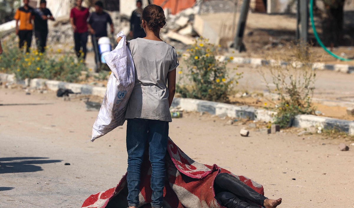 فتاة فلسطينية قرب جثة شهيد سقط أثناء انتظاره الحصول على حصة غذائية في النصيرات وسط القطاع (أ ف ب)