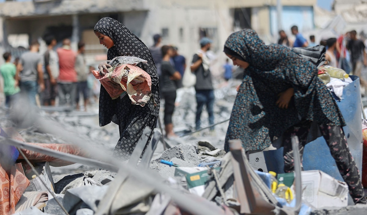 فلسطينيتان تبحثان عن أغراض صالحة بين ركام برج «طيبة» الذي دمّره العدو في مدينة غزة (أ ف ب)