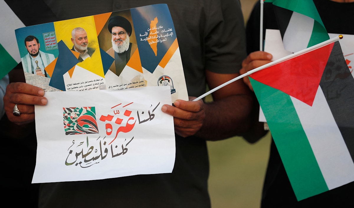 عراقيون يرفعون أعلاماً فلسطينية وصور قادة المقاومة خلال مسيرة في بغداد (أ ف ب)