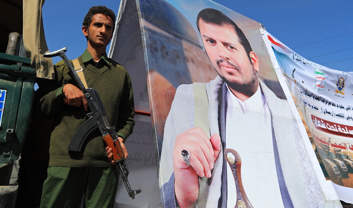 مقاتل من «أنصار الله» يحرس قرب صورة لزعيم الحركة، عبد الملك الحوثي، أثناء مهرجان في صنعاء (أ ف ب)