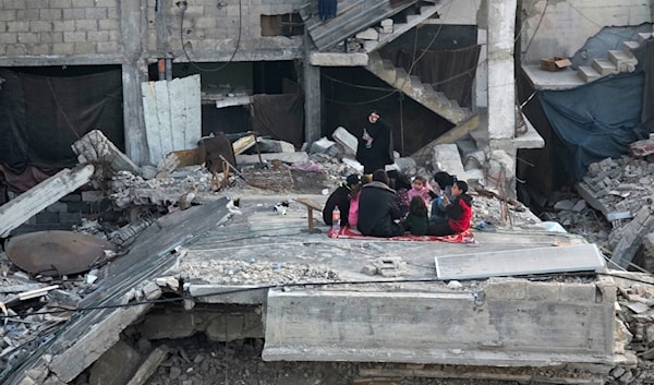 تتجمع عائلة فلسطينية لتناول إفطار رمضان فوق أنقاض منزلها الذي دمّره القصف الإسرائيلي في خانيونس (APA)