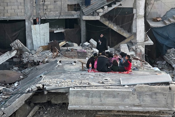 تتجمع عائلة فلسطينية لتناول إفطار رمضان فوق أنقاض منزلها الذي دمّره القصف الإسرائيلي في خانيونس (APA)
