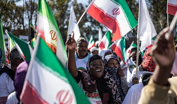 متظاهرون في بريتوريا يلوّحون بالأعلام الإيرانية أثناء تجمعهم أمام القنصلية الأميركية (أ ف ب)