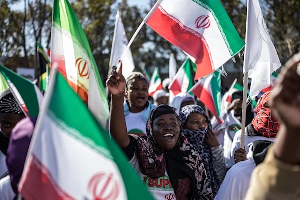 متظاهرون في بريتوريا يلوّحون بالأعلام الإيرانية أثناء تجمعهم أمام القنصلية الأميركية (أ ف ب)