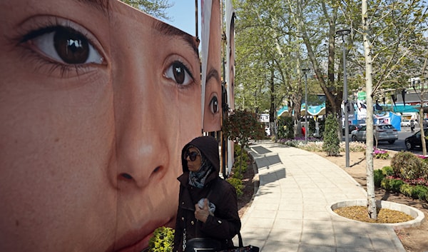 إيرانية في طهران تعبر قرب ملصق لإحدى ضحايا القصف الأميركي على مدرسة ميناب جنوب إيران (أ ف ب)
