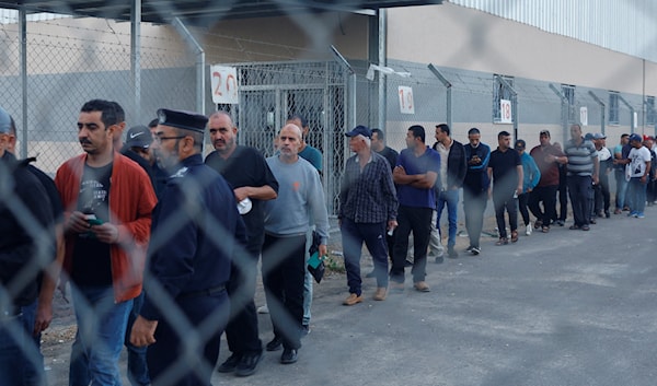 عمال فلسطينيون عند إحدى نقاط العبور إلى الداخل المحتل (رويترز)