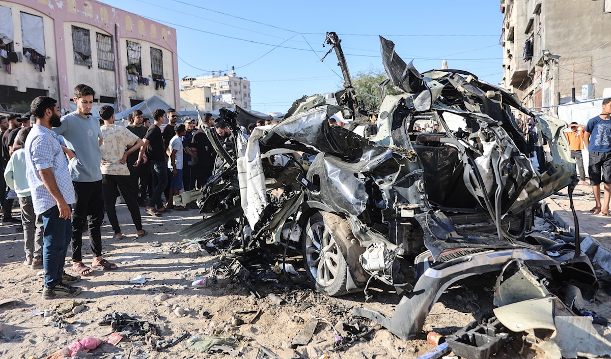 فلسطينيون يشاهدون حطام سيارة تعرّضت لضربة من طائرة إسرائيلية في مدينة غزة (أ ف ب)