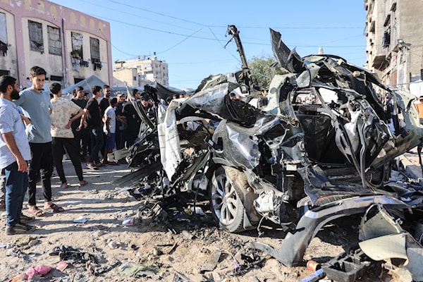 فلسطينيون يشاهدون حطام سيارة تعرّضت لضربة من طائرة إسرائيلية في مدينة غزة (أ ف ب)