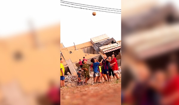 أطفال يلعبون كرة القدم أمام مبنى مدمر في بلدة كفررمان (الأخبار)