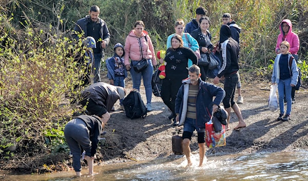 أفراد يعبرون النهر الكبير الفاصل بين لبنان وسوريا في الشمال (أ ف ب)