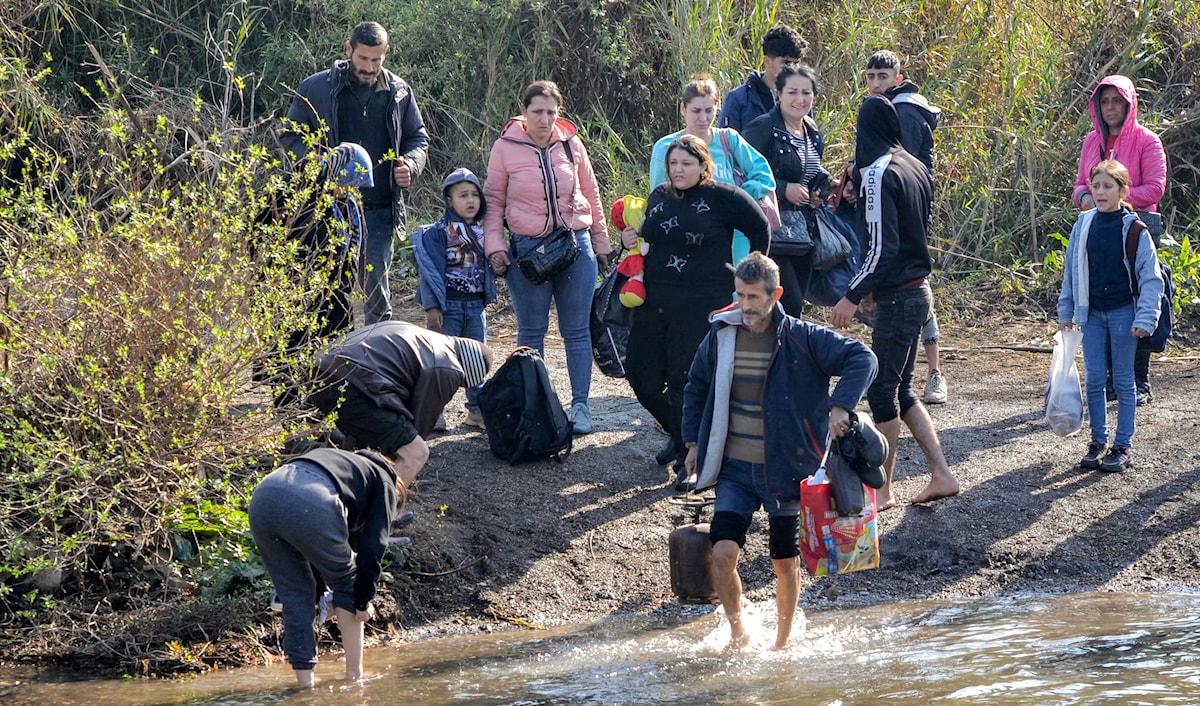 أفراد يعبرون النهر الكبير الفاصل بين لبنان وسوريا في الشمال (أ ف ب)