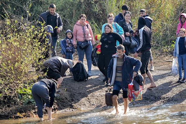 أفراد يعبرون النهر الكبير الفاصل بين لبنان وسوريا في الشمال (أ ف ب)