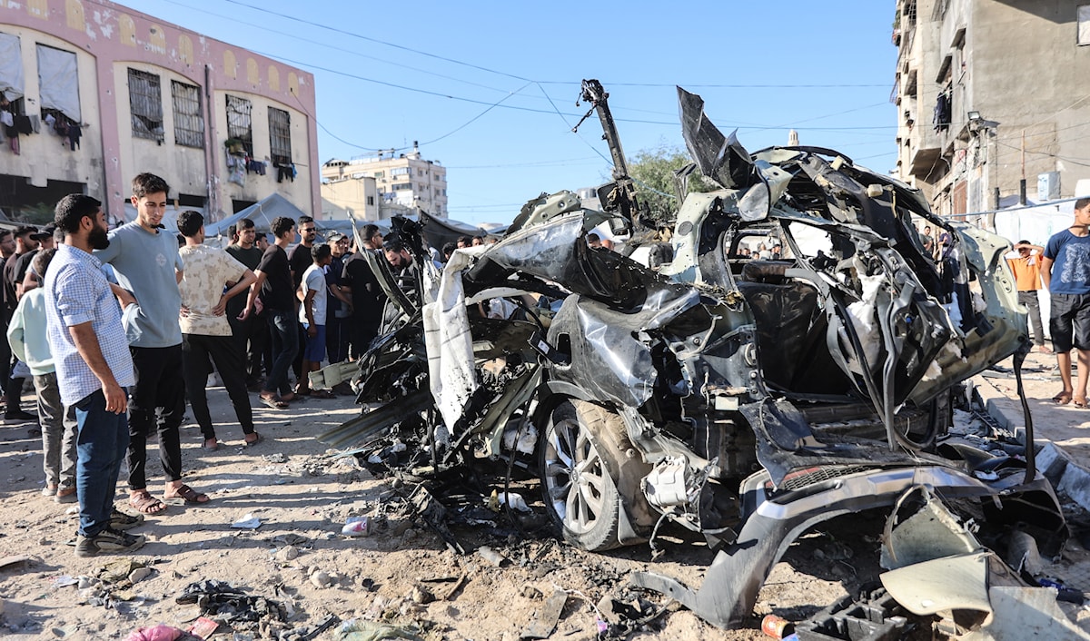فلسطينيون يشاهدون حطام سيارة تعرّضت لضربة من طائرة إسرائيلية في مدينة غزة (أ ف ب)