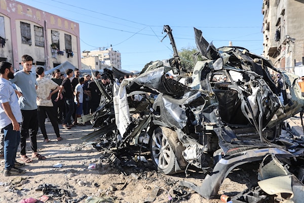 فلسطينيون يشاهدون حطام سيارة تعرّضت لضربة من طائرة إسرائيلية في مدينة غزة (أ ف ب)