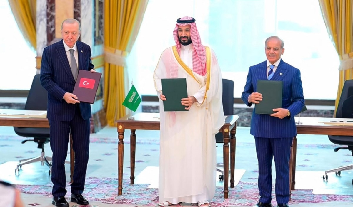 القادة الثلاثة، يحملون وثائق «اتفاقية مكة للدفاع المشترك» عقب التوقيع (أ ف ب)