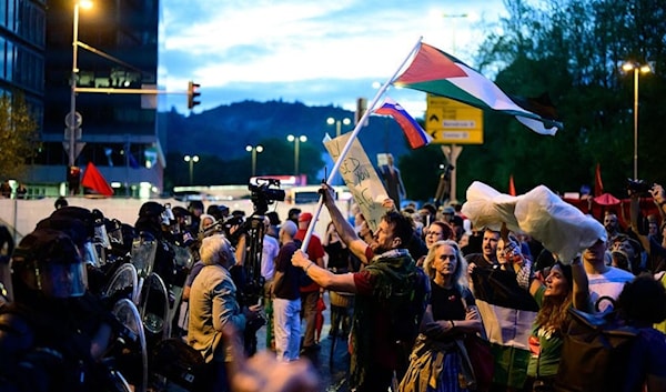متظاهرون في ليوبليانا في مواجهة صف من عناصر شرطة مكافحة الشغب، مع علم فلسطيني ولافتات، مساء افتتاح السفارة (من الويب)